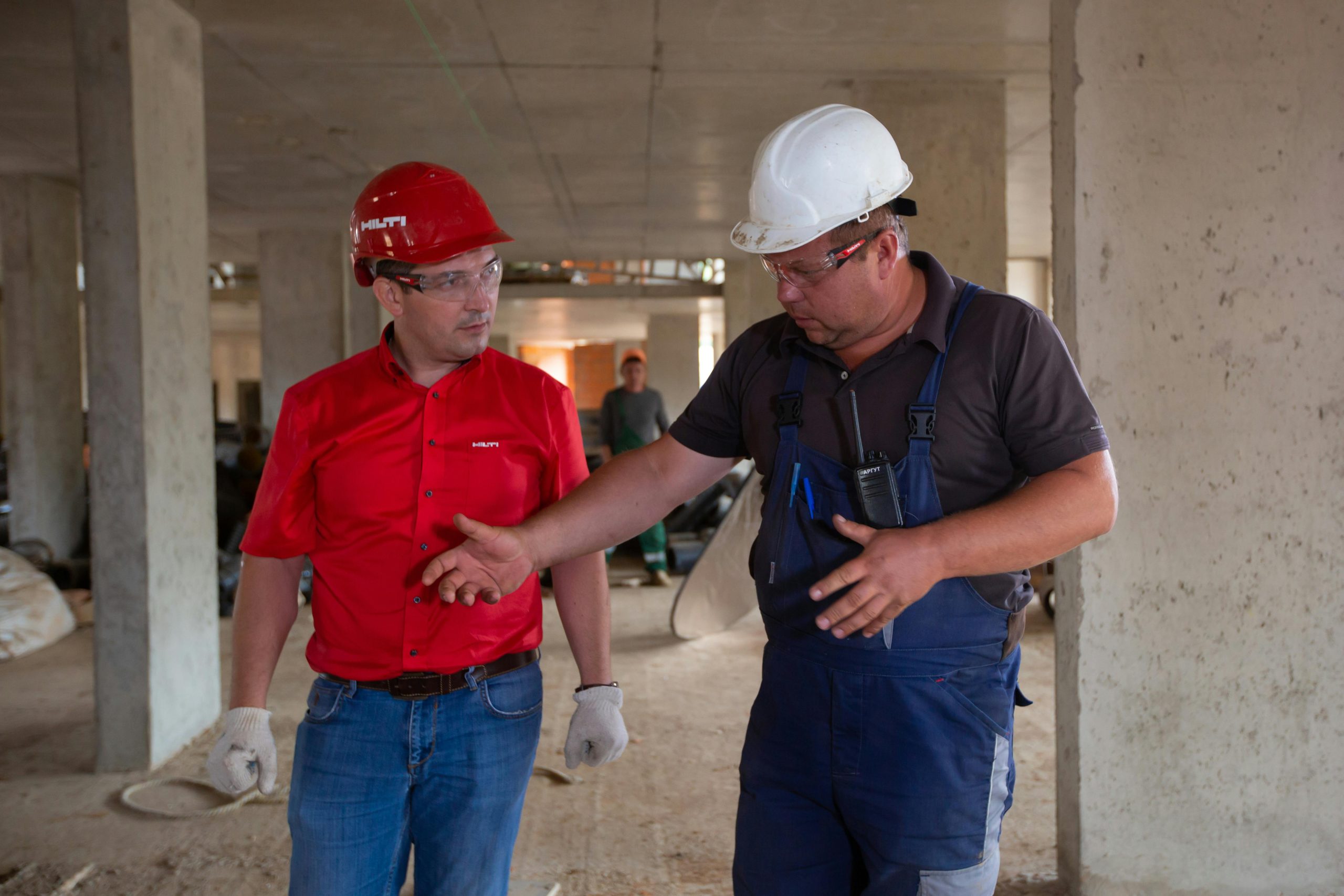 Two workers in hard hats reviewing safety procedures at a construction site