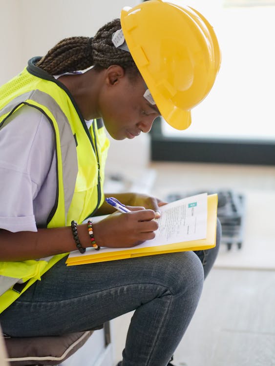 EHS worker in safety vest writing near-miss report on clipboard