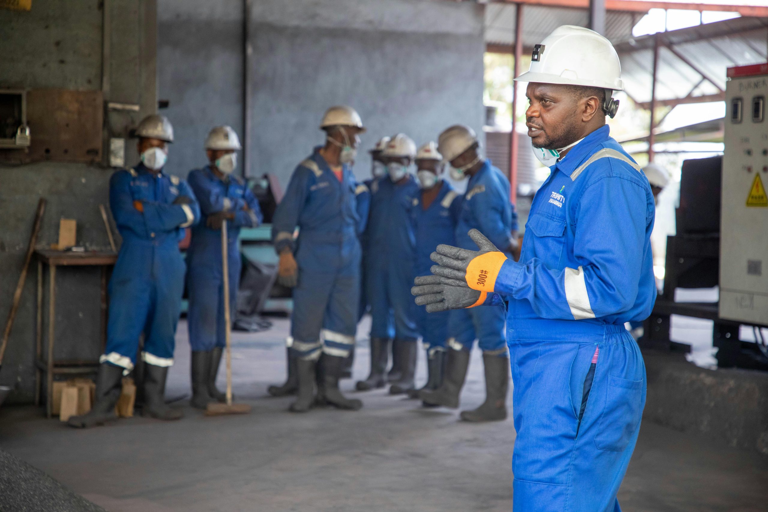 Group of industrial workers in safety gear participating in a training session on the factory floor