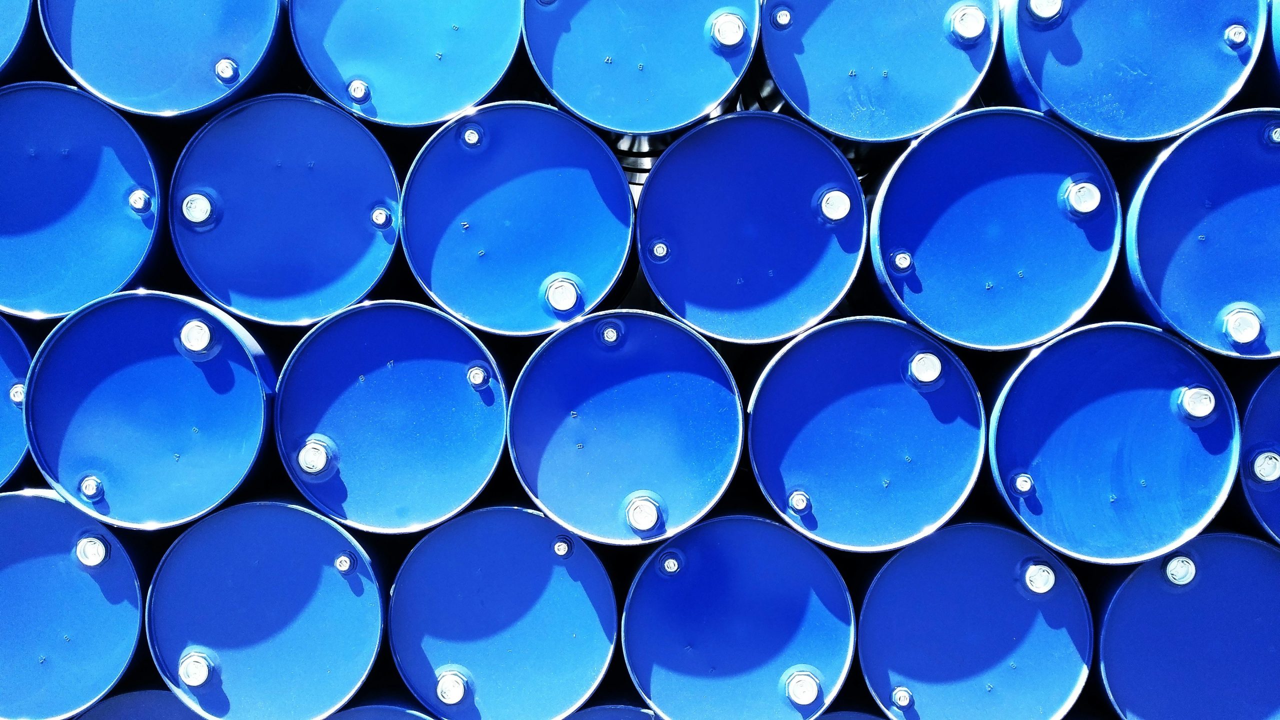 Top-down aerial view of stacked blue industrial chemical drums in a storage area