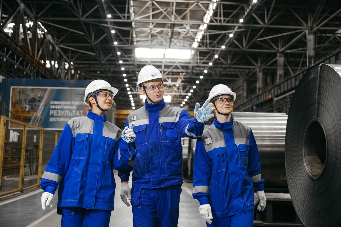 Industrial workers in safety gear conducting a job hazard analysis in a manufacturing facility