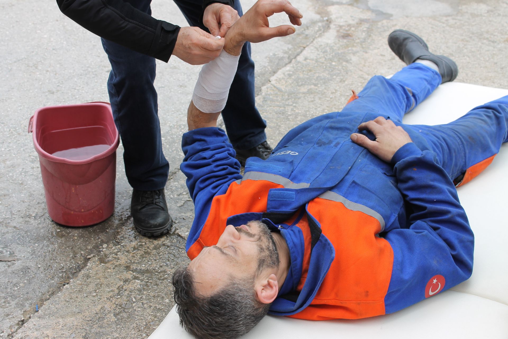 Coworker applying a bandage to an injured worker's arm at a worksite, the moment a recordability decision begins