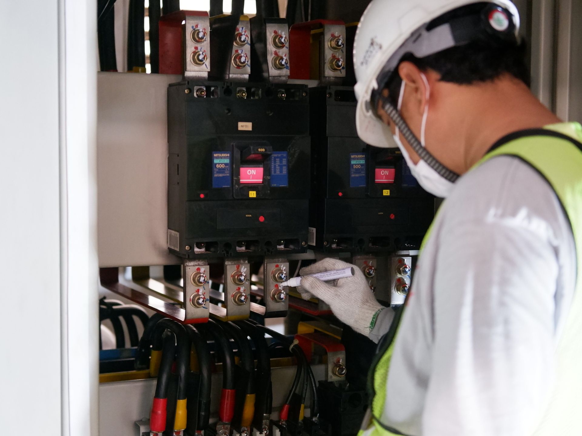 Technician wearing PPE inspecting electrical panels during a workplace safety inspection