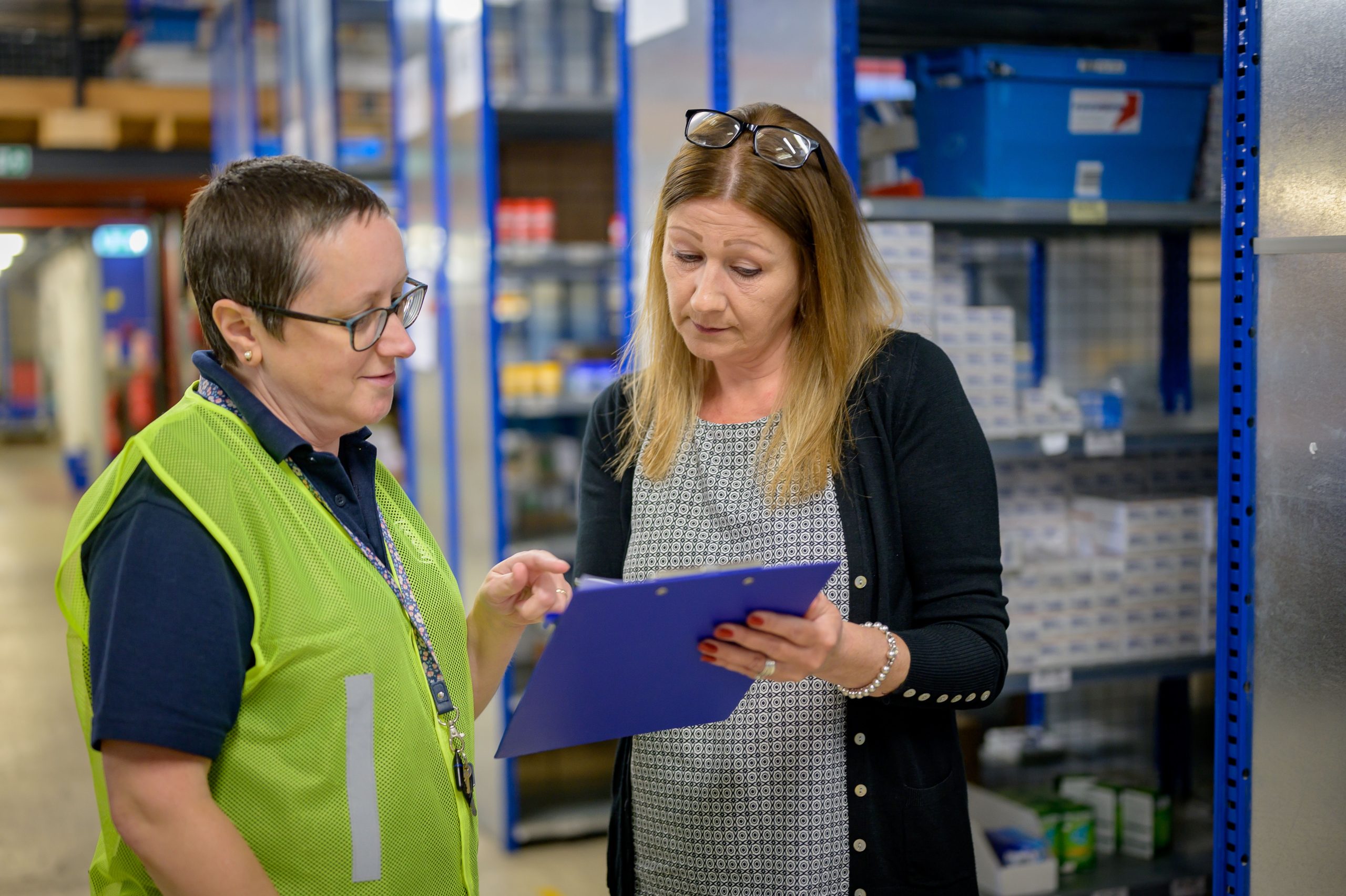 Supervisor and warehouse worker reviewing a clipboard to verify training competency