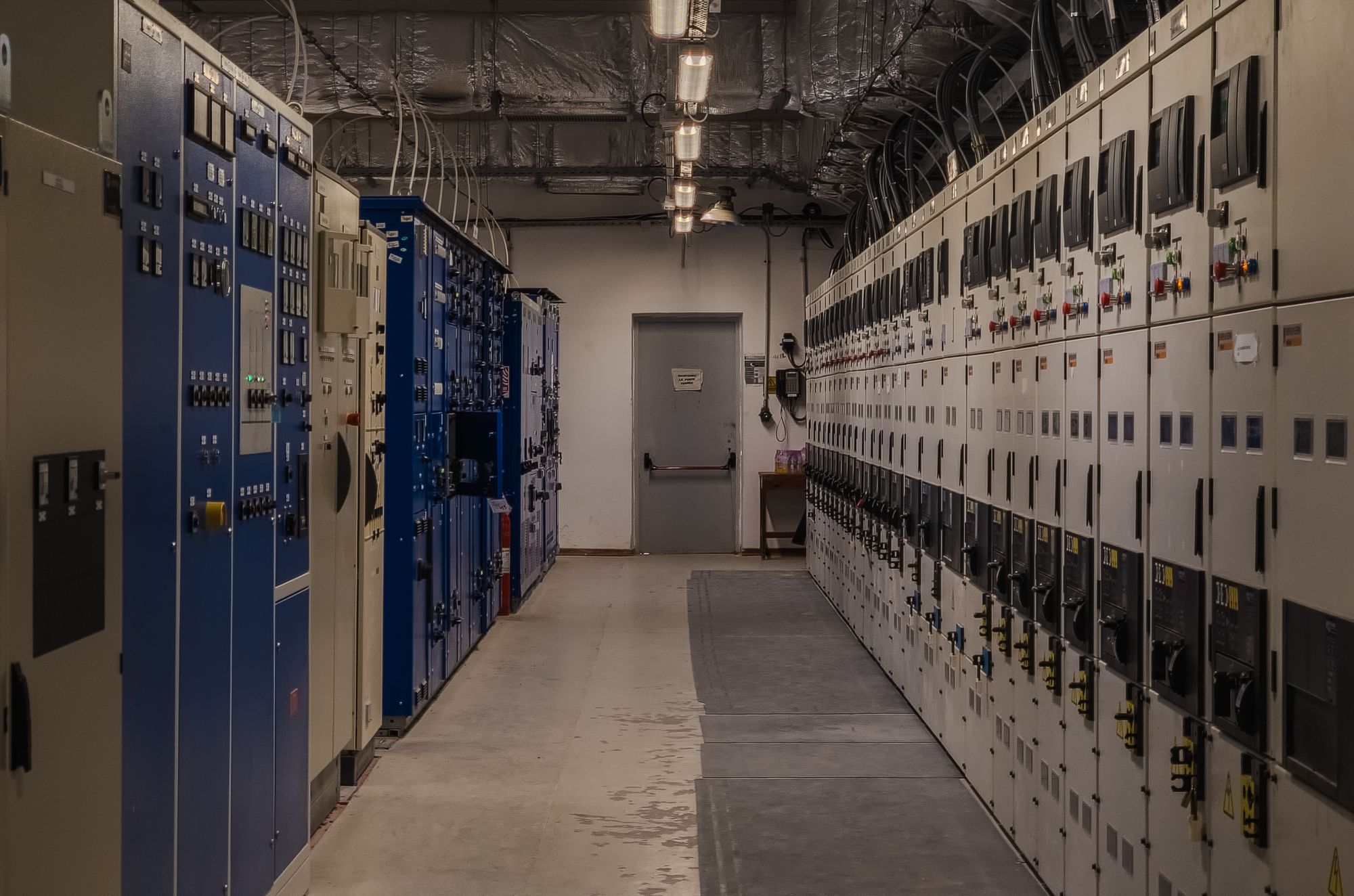 Row of industrial switchgear and motor control center panels in a plant electrical room, the energy isolating devices a lockout procedure has to name