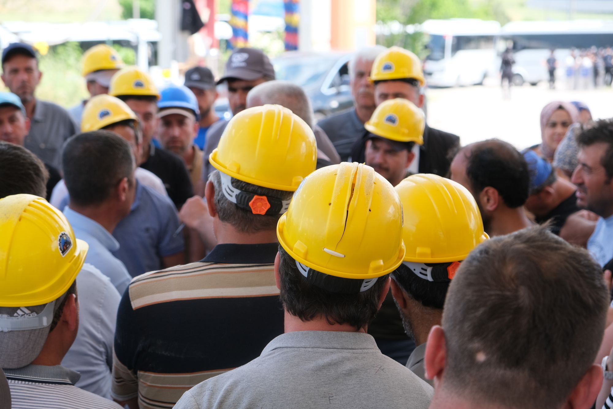 Construction crew in yellow hard hats gathered around a supervisor for a morning briefing